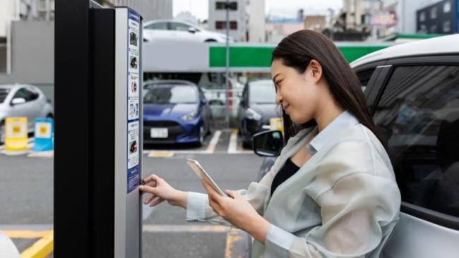 Žena platí u parkovacího automatu